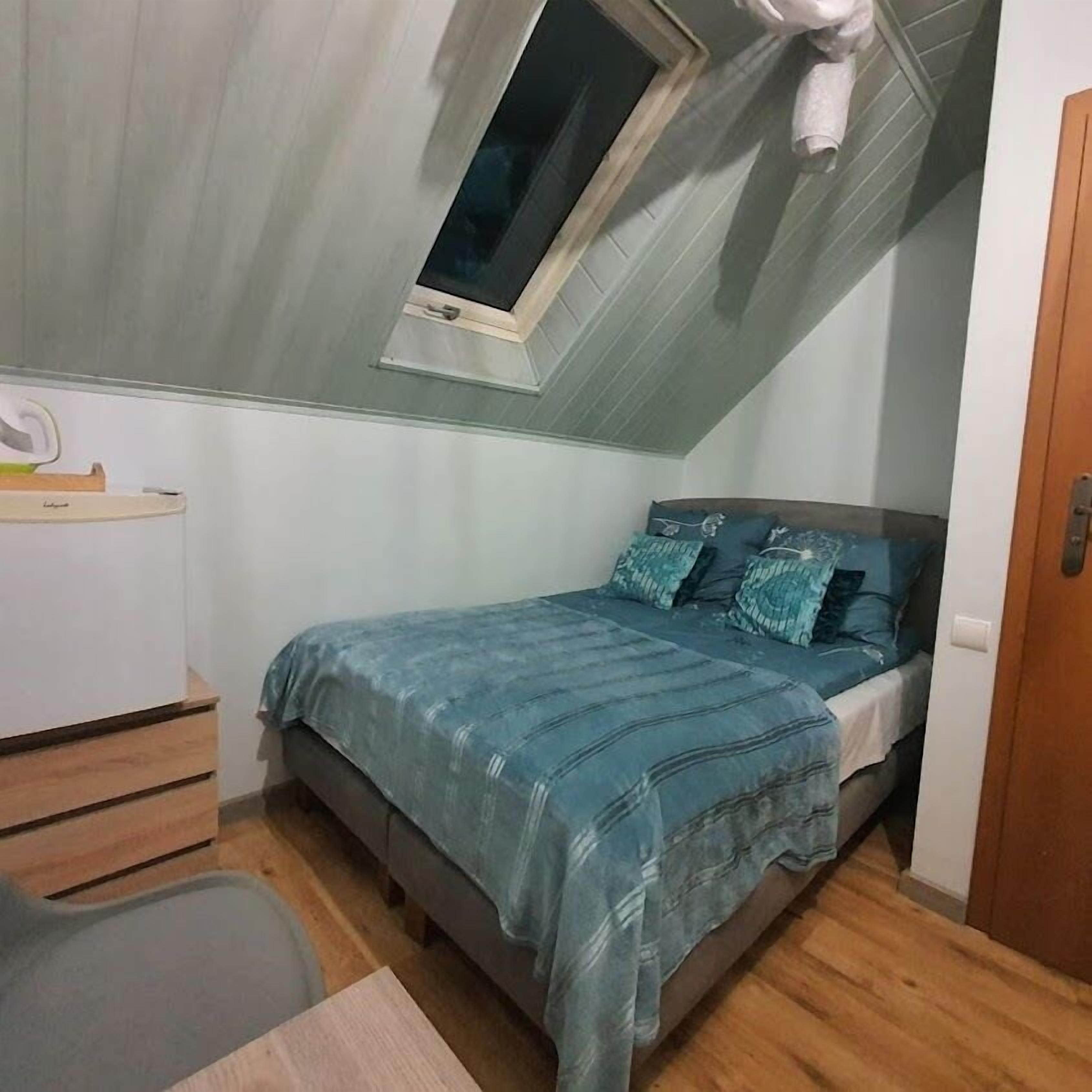 A compact bedroom with a single bed, a small desk, and a window.