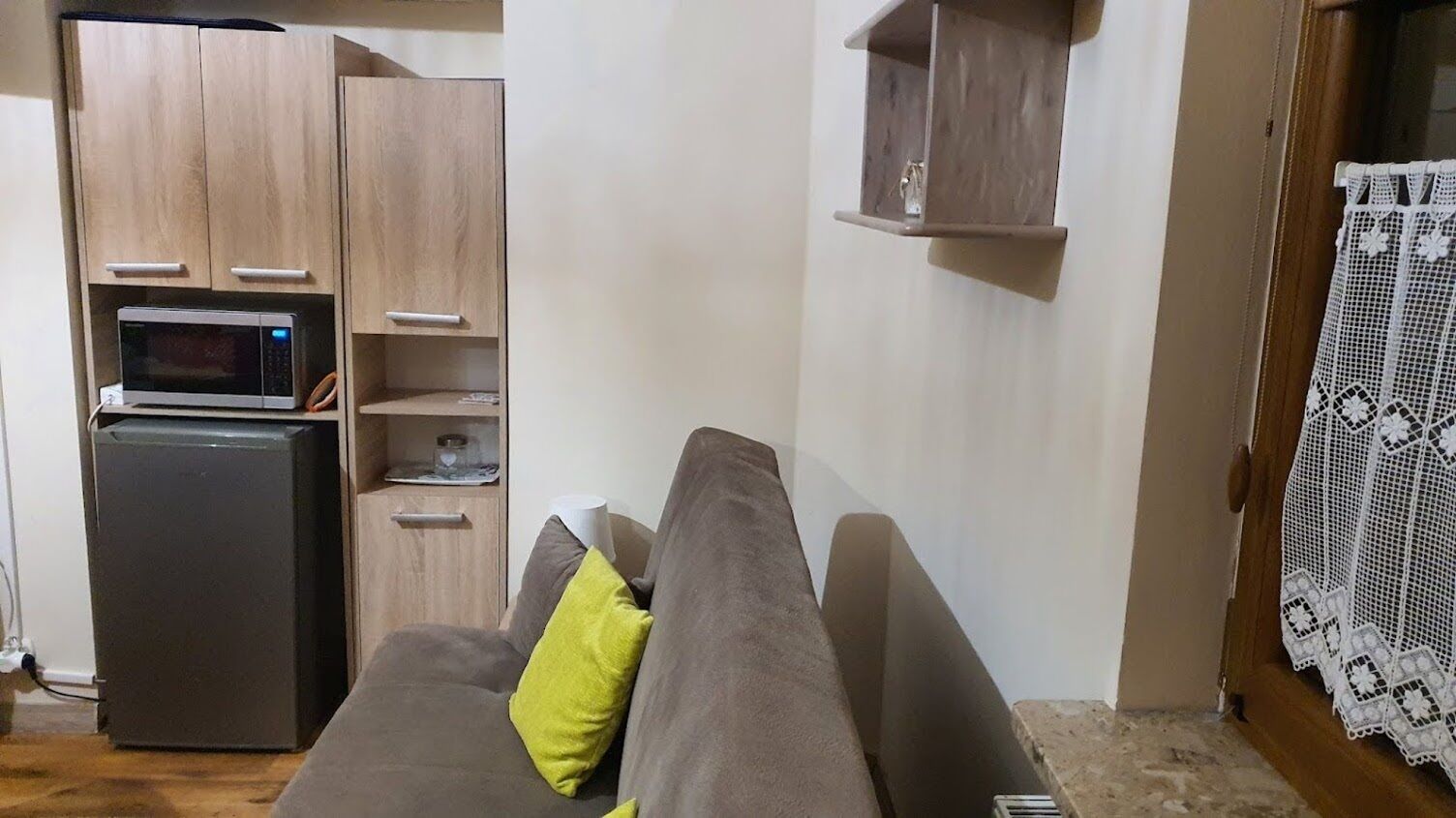 A living room with a sofa, a microwave, and a small refrigerator.