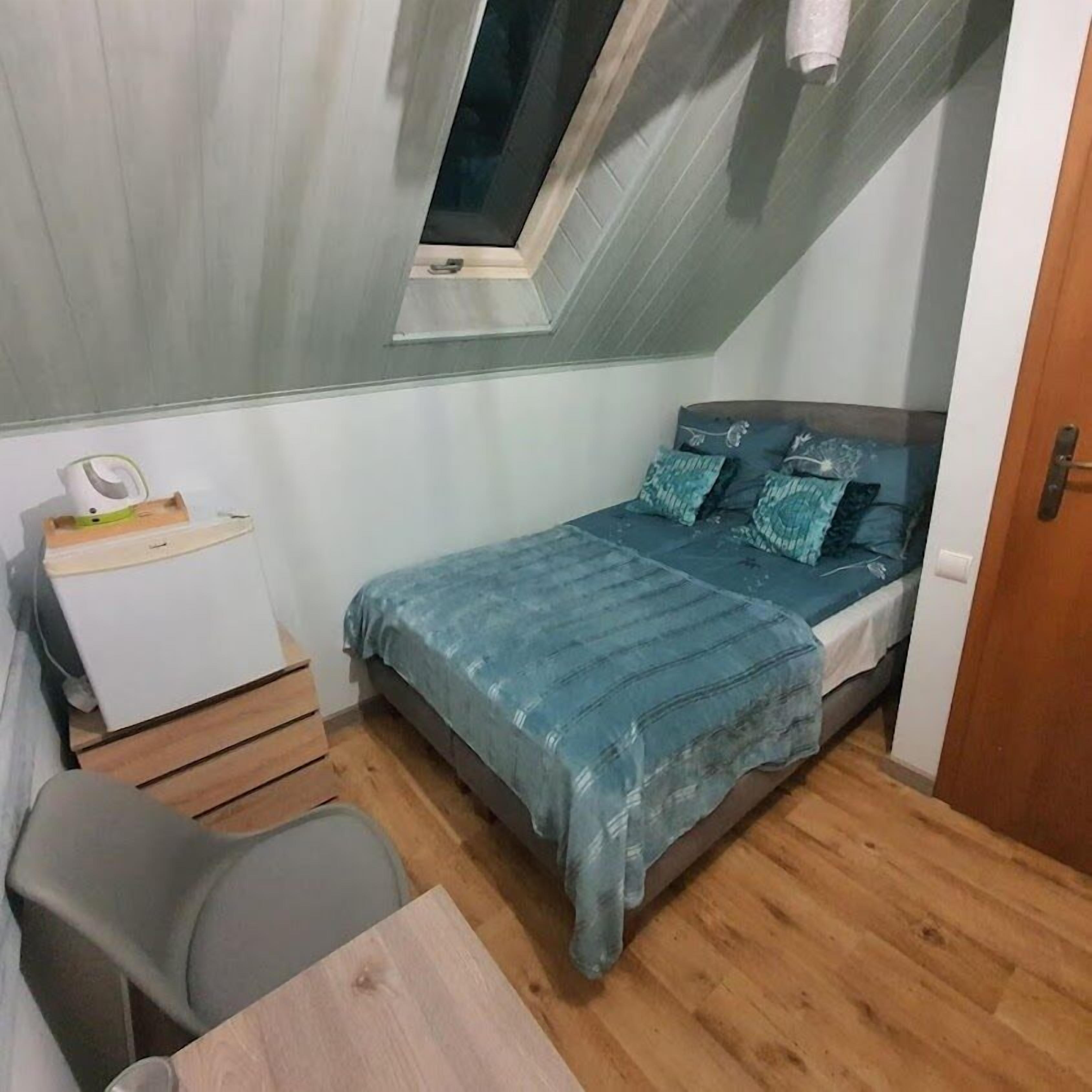 A small, compact room with a bed, a desk, and a chair.