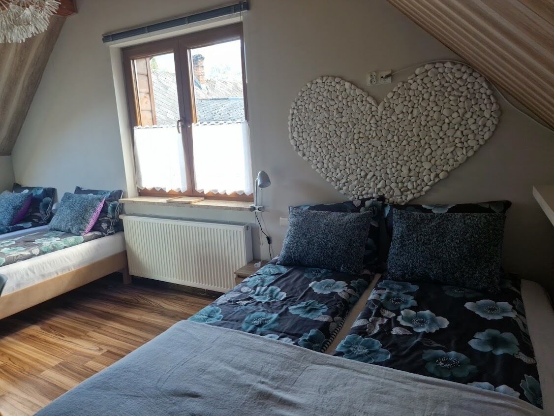 Un dormitorio con cama de altillo, un adorno de pared con forma de corazón y una ventana con vistas.