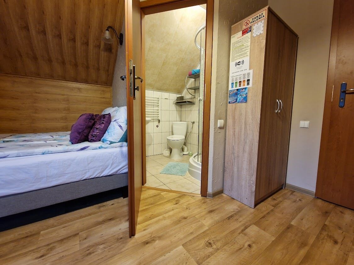 Een slaapkamer met een bed, een houten kledingkast en een badkamer die door een open deur zichtbaar is.