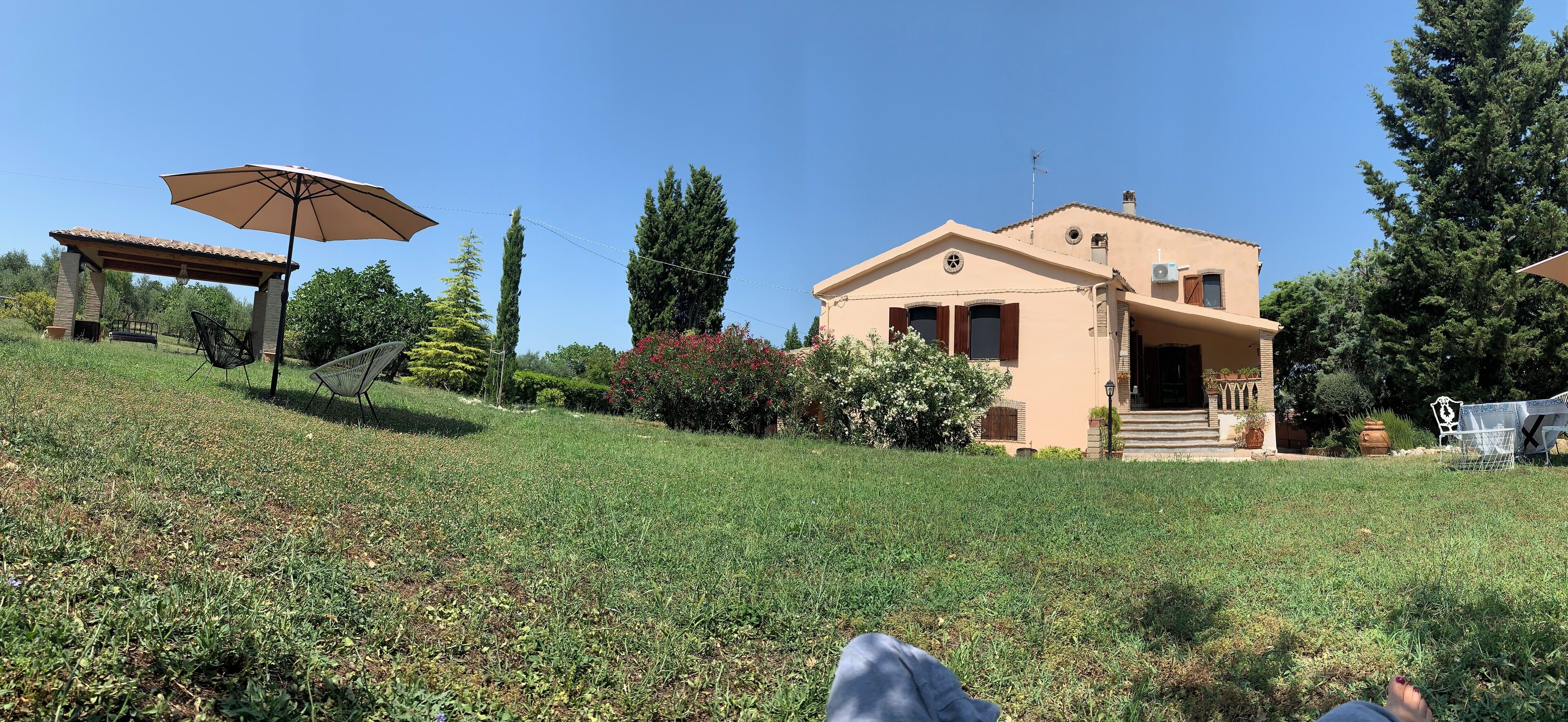 Una casa con patio coperto, giardino e prato.