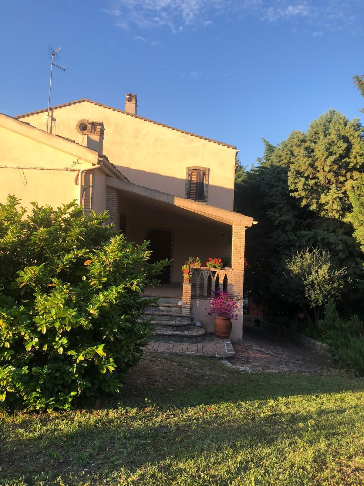 A two-story house with a small porch, a chimney, and a satellite dish.