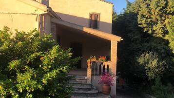 A two-story house with a small porch, a chimney, and a satellite dish.