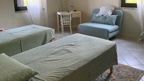 Ein Zimmer mit zwei Betten, einem Schreibtisch, einem Stuhl, einem Fernseher und einem Fenster mit Vorhängen.
