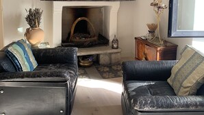 Ein Wohnzimmer mit Kamin, zwei Ledersofas, einem Couchtisch und verschiedenen Dekorationselementen.