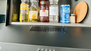 A storage compartment with various items including bottles, a can, and a sponge. - Studio Royal (Saint-Omer)