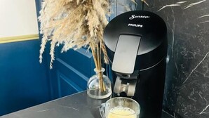 A coffee machine with a glass cup of coffee on a marble countertop, surrounded by dried pampas grass. - Studio Royal (Saint-Omer)