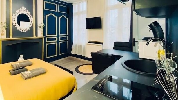 A modern hotel room with a bed, a desk, a sink, and a large mirror. - Studio Royal (Saint-Omer)