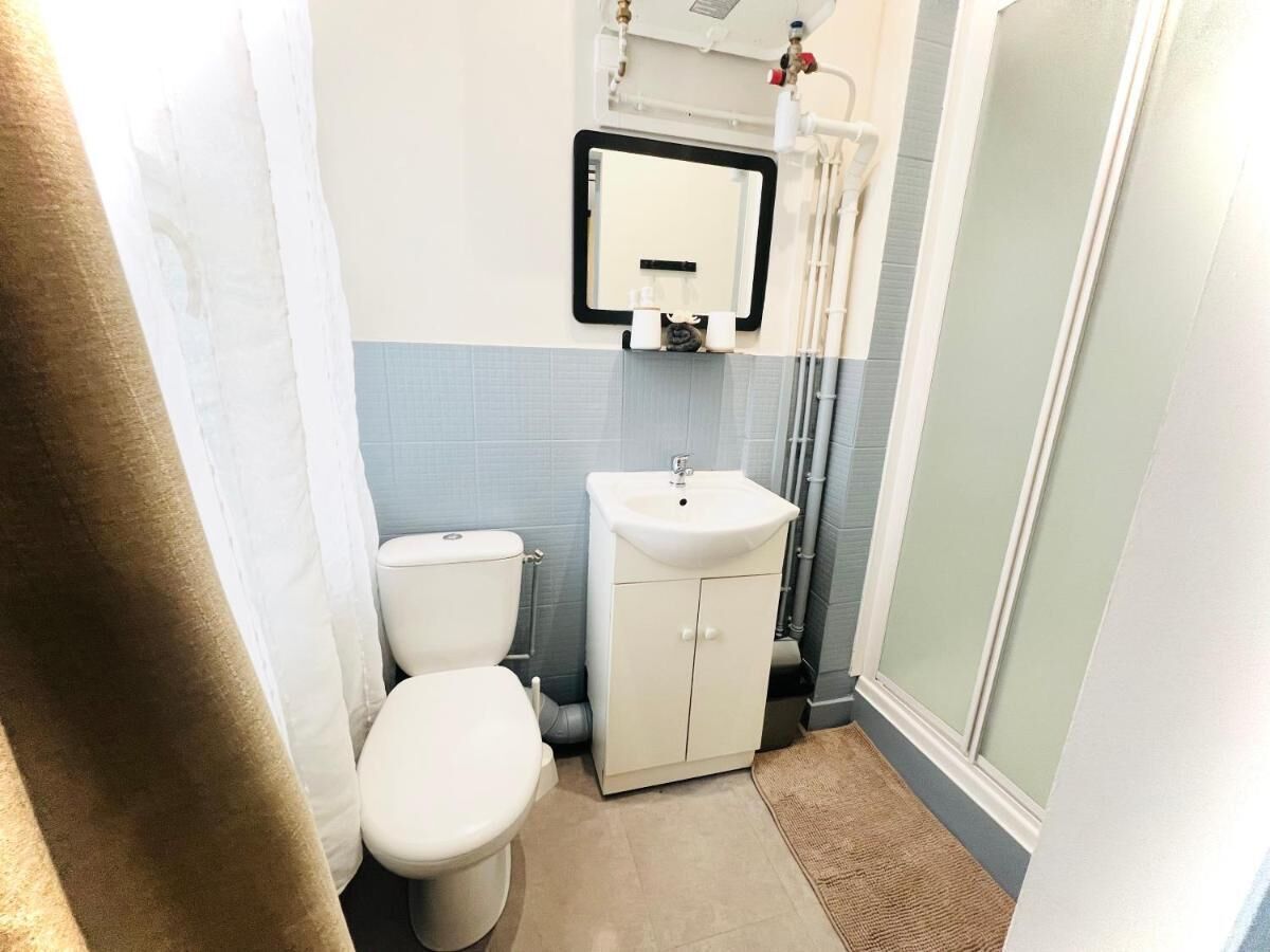 A small bathroom with a toilet, sink, and shower.
