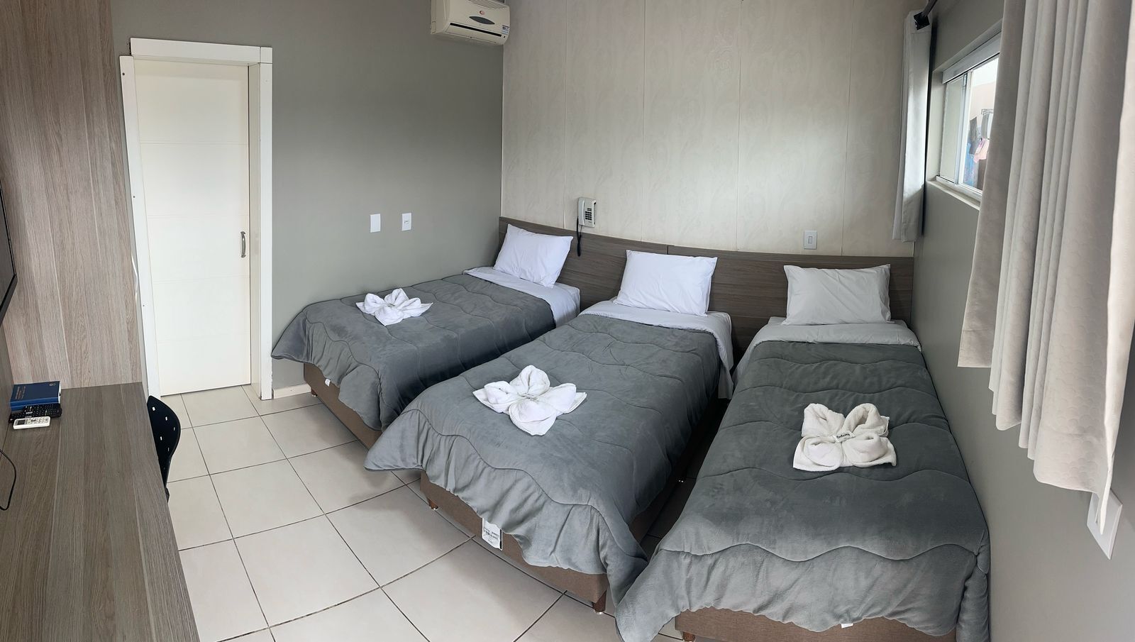 A hotel room with two beds, a desk, and a door.