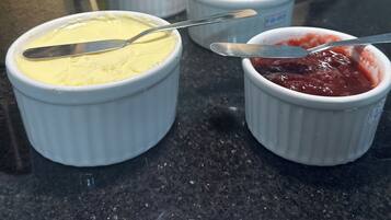 Una encimera de cocina con diversos alimentos y bebidas, incluyendo una jarra de líquido amarillo, una jarra de líquido blanco y varios recipientes pequeños con diferentes salsas.