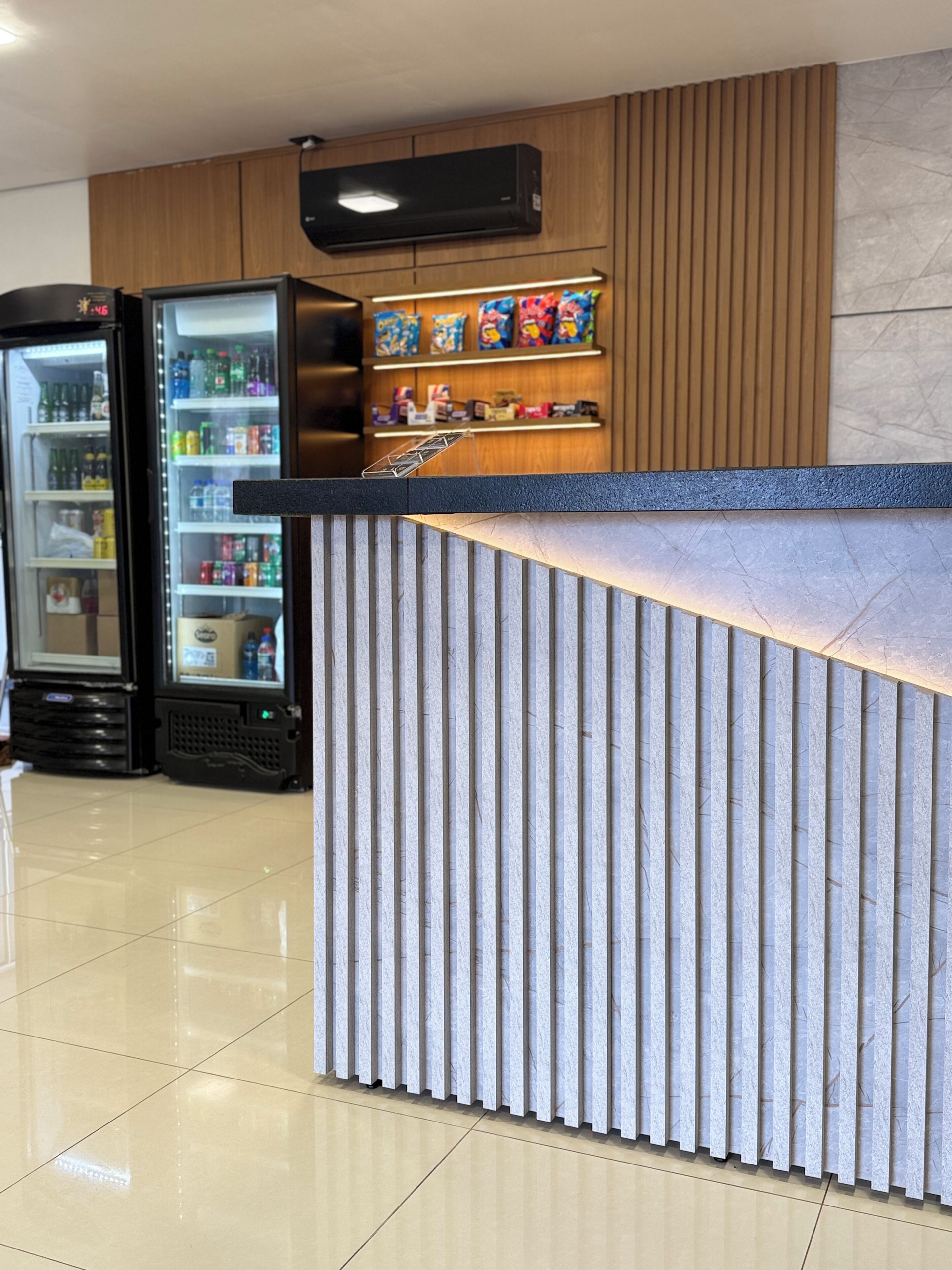 A reception area with a counter, a refrigerator stocked with beverages, and a shelf with snacks.