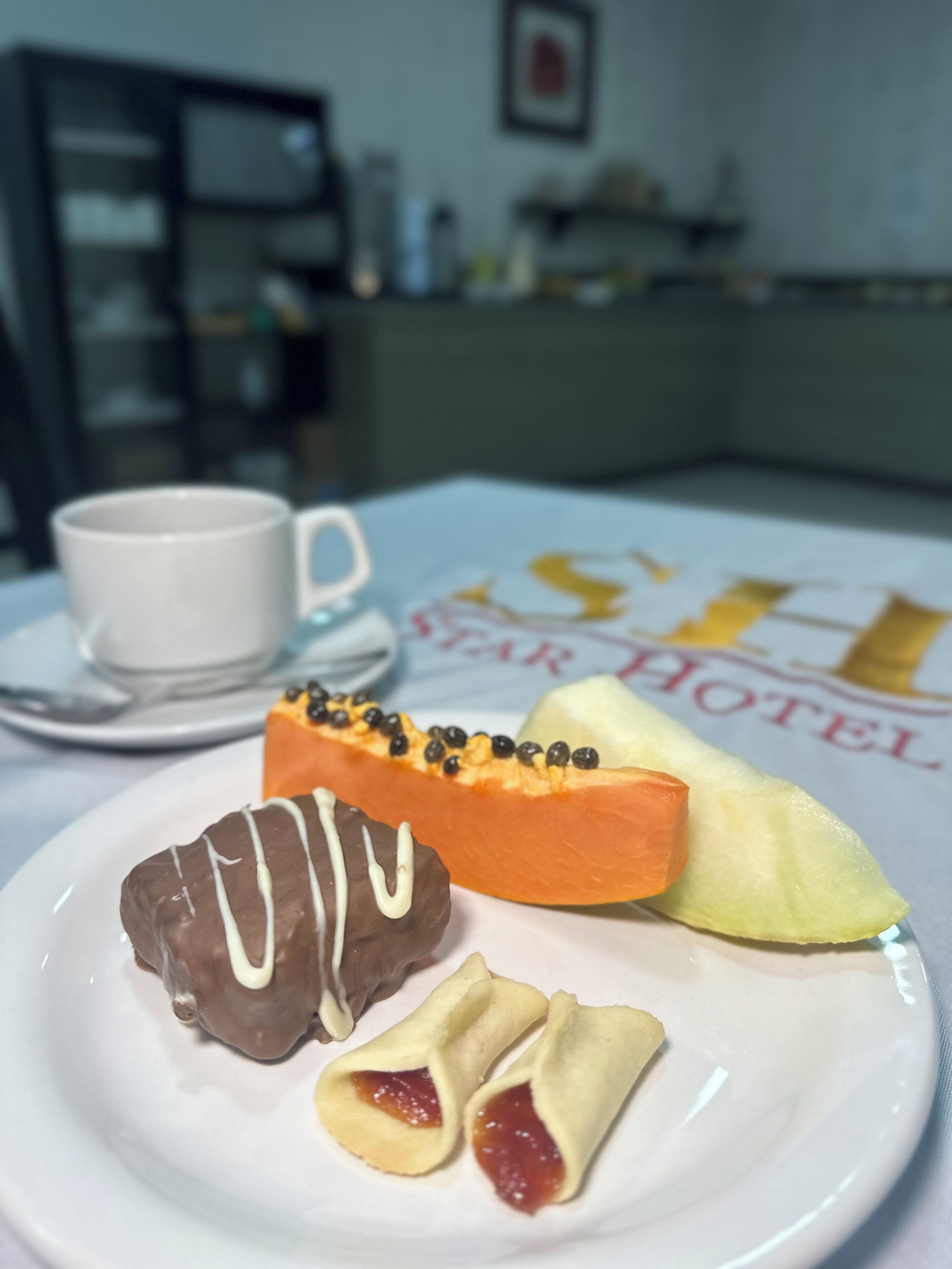 A plate with pastries and a slice of fruit on a table in a hotel room.