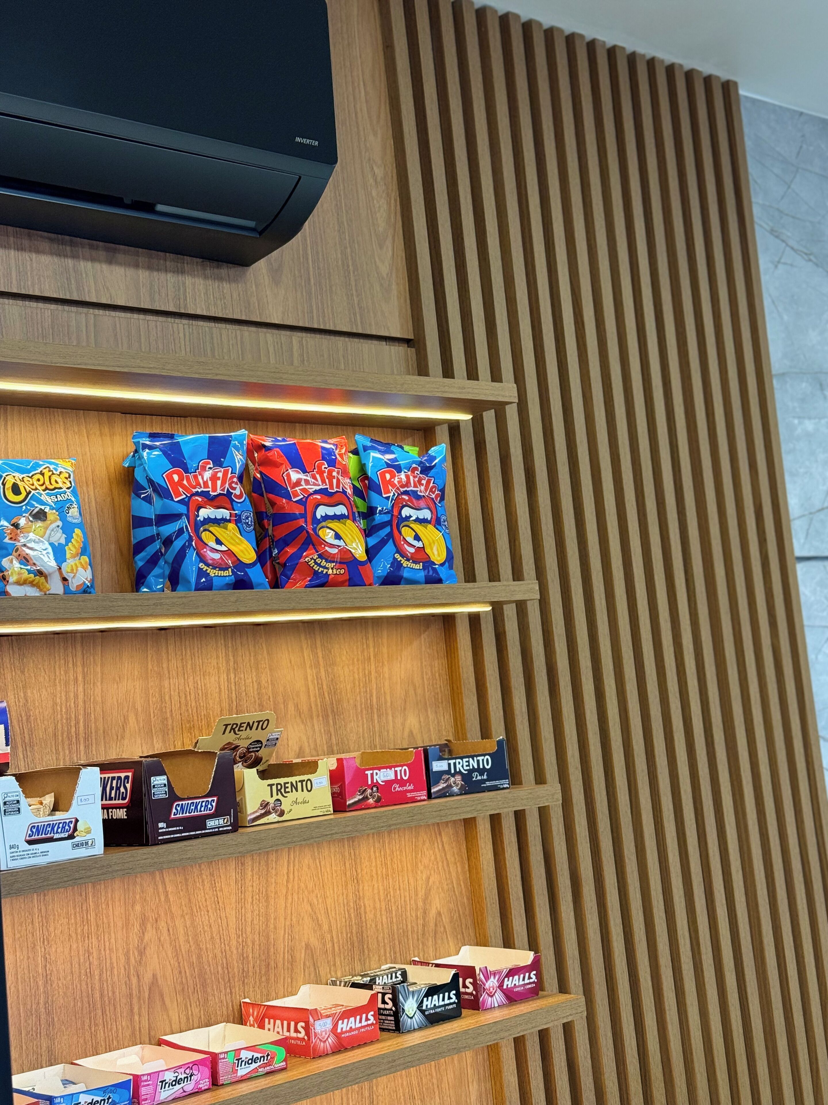 A snack display with various brands including Trento, Snickers, and Halls.
