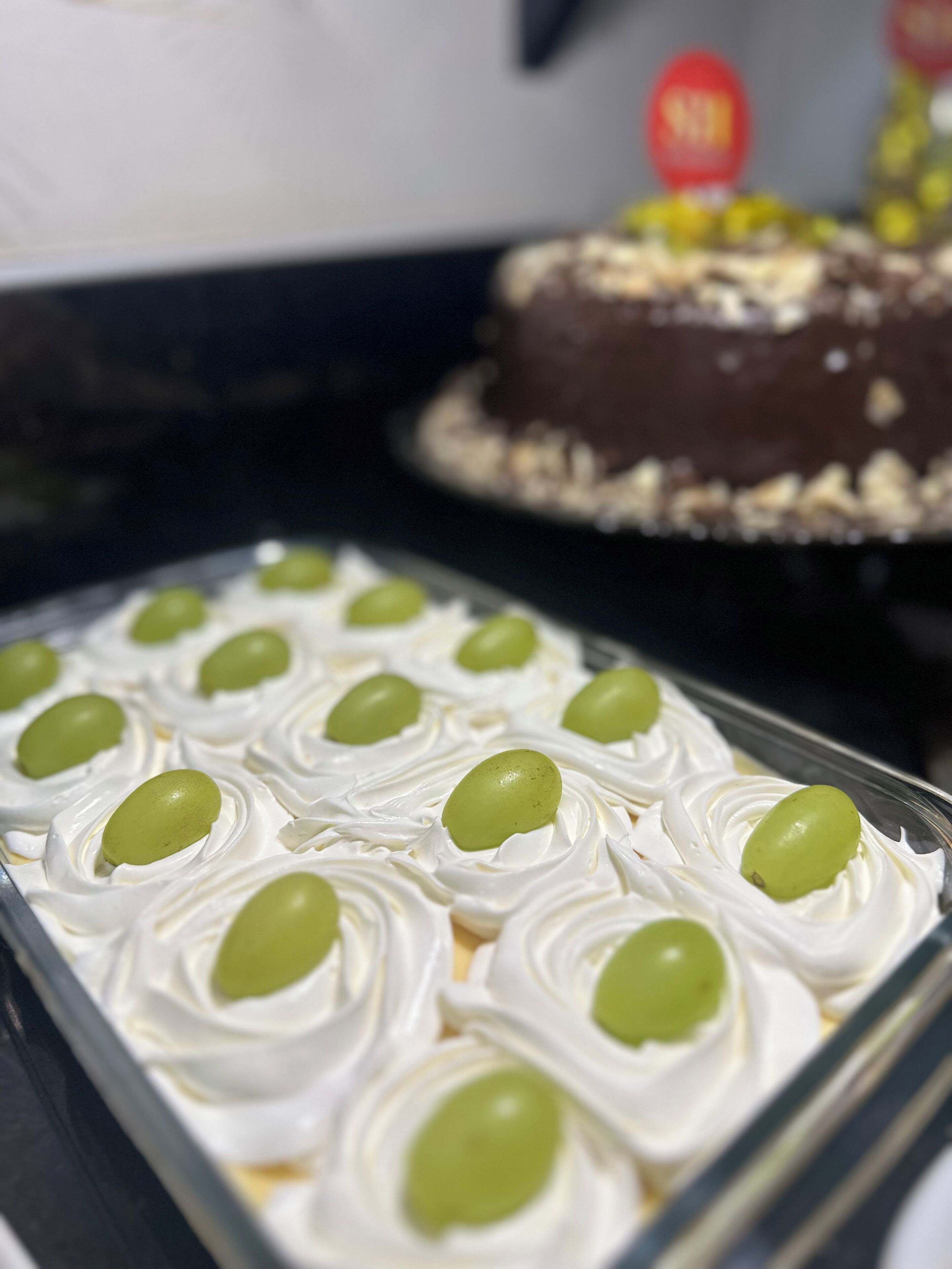 A tray of desserts with white whipped cream and green olives.