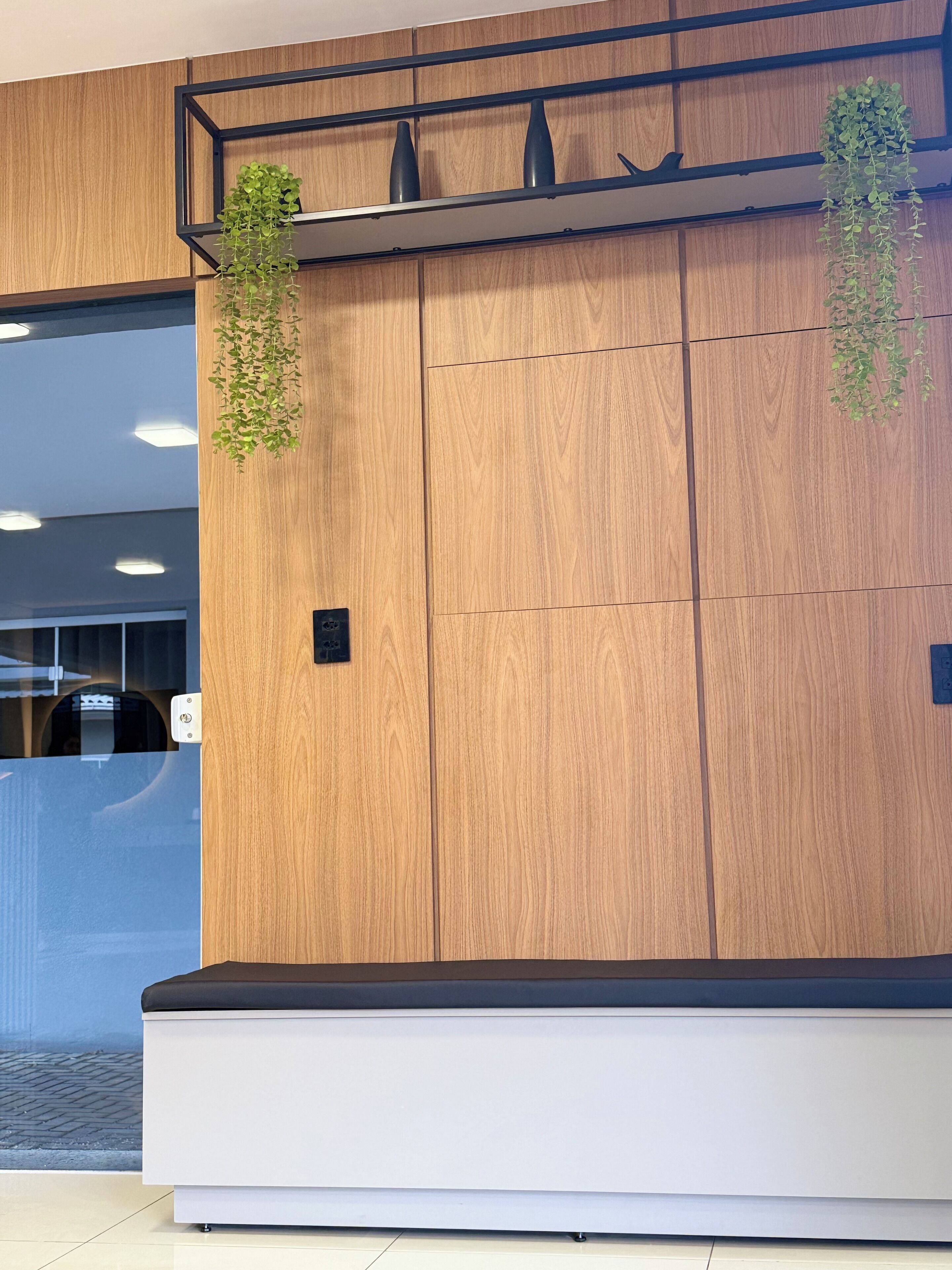 A reception area with a wooden panel wall, a reception desk, and hanging plants.