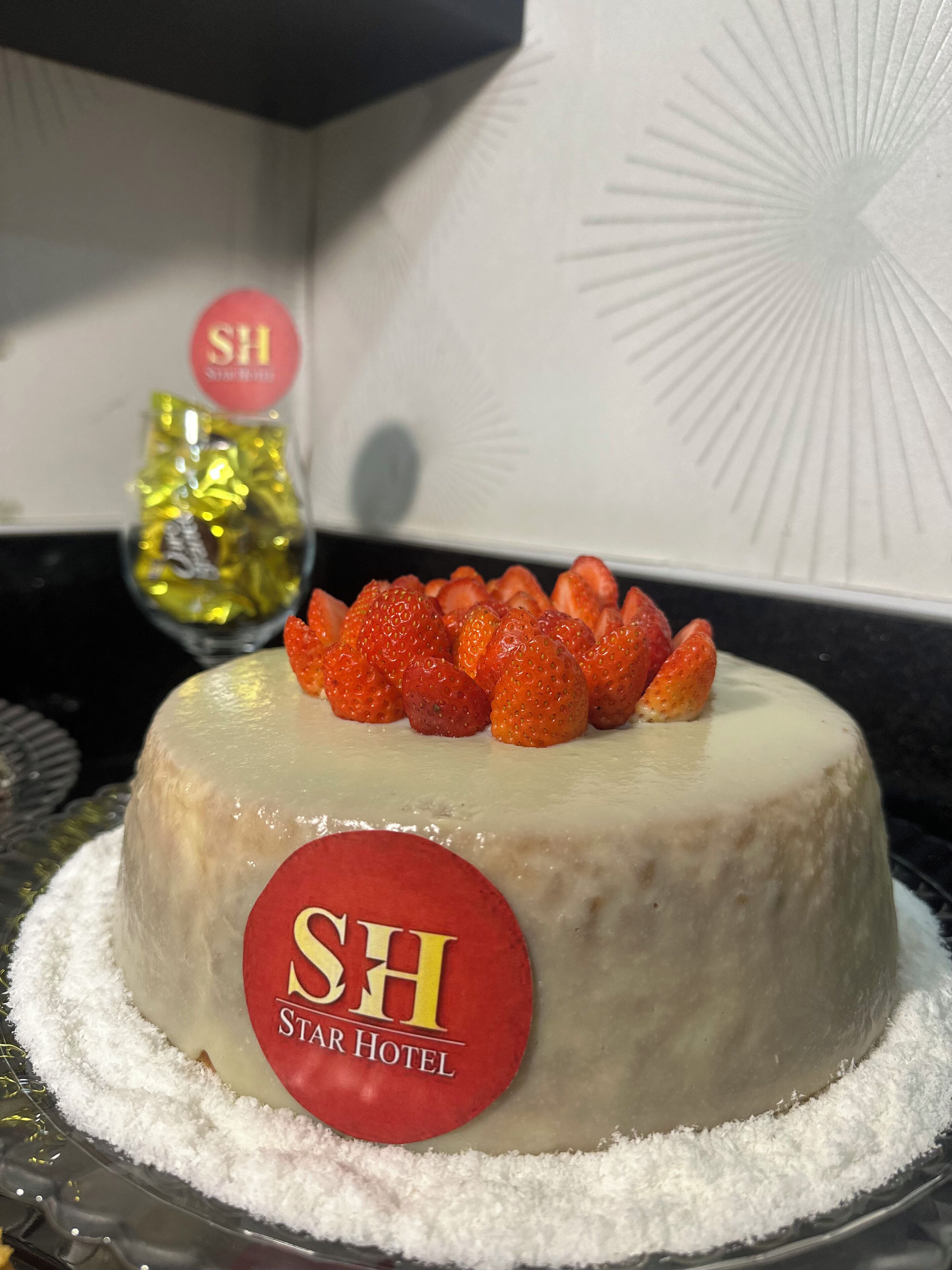 Un gâteau décoré de fraises et portant une étiquette sur laquelle on peut lire « SH Star Hotel ».