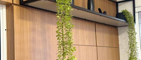 A wooden wall with a black metal shelf holding two black vases and a hanging green plant.