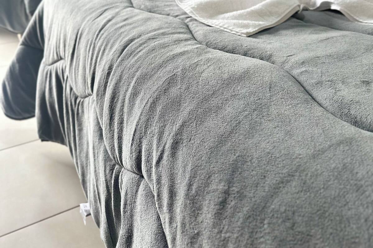 A hotel room with two beds, each with grey bedding and white pillows.