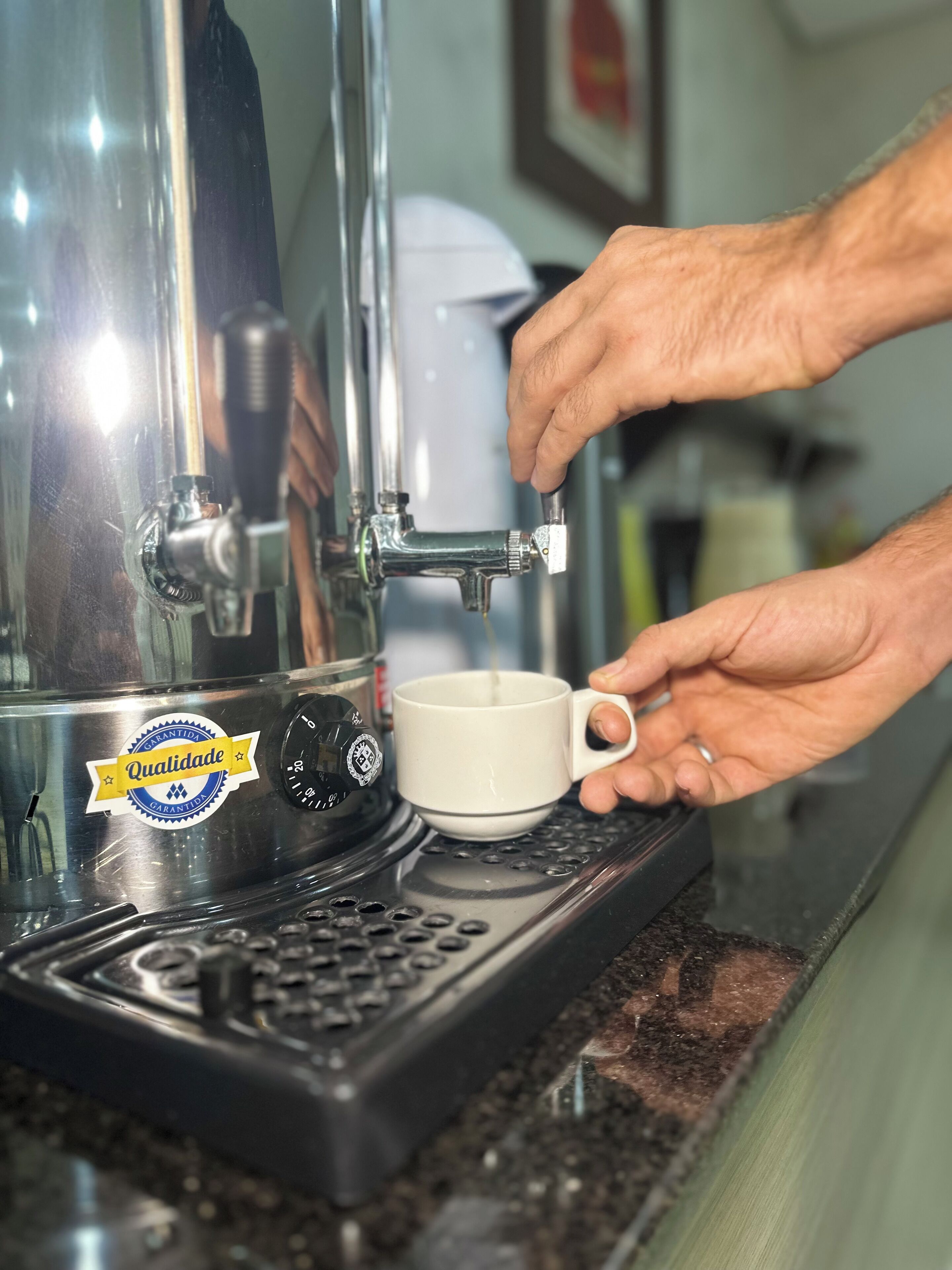 Iemand bedient een koffieapparaat en schenkt koffie in een kop.