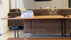 A modern living room with a brown sofa, a wooden coffee table, and a mounted TV. - STAR HOTEL (Chapecó)