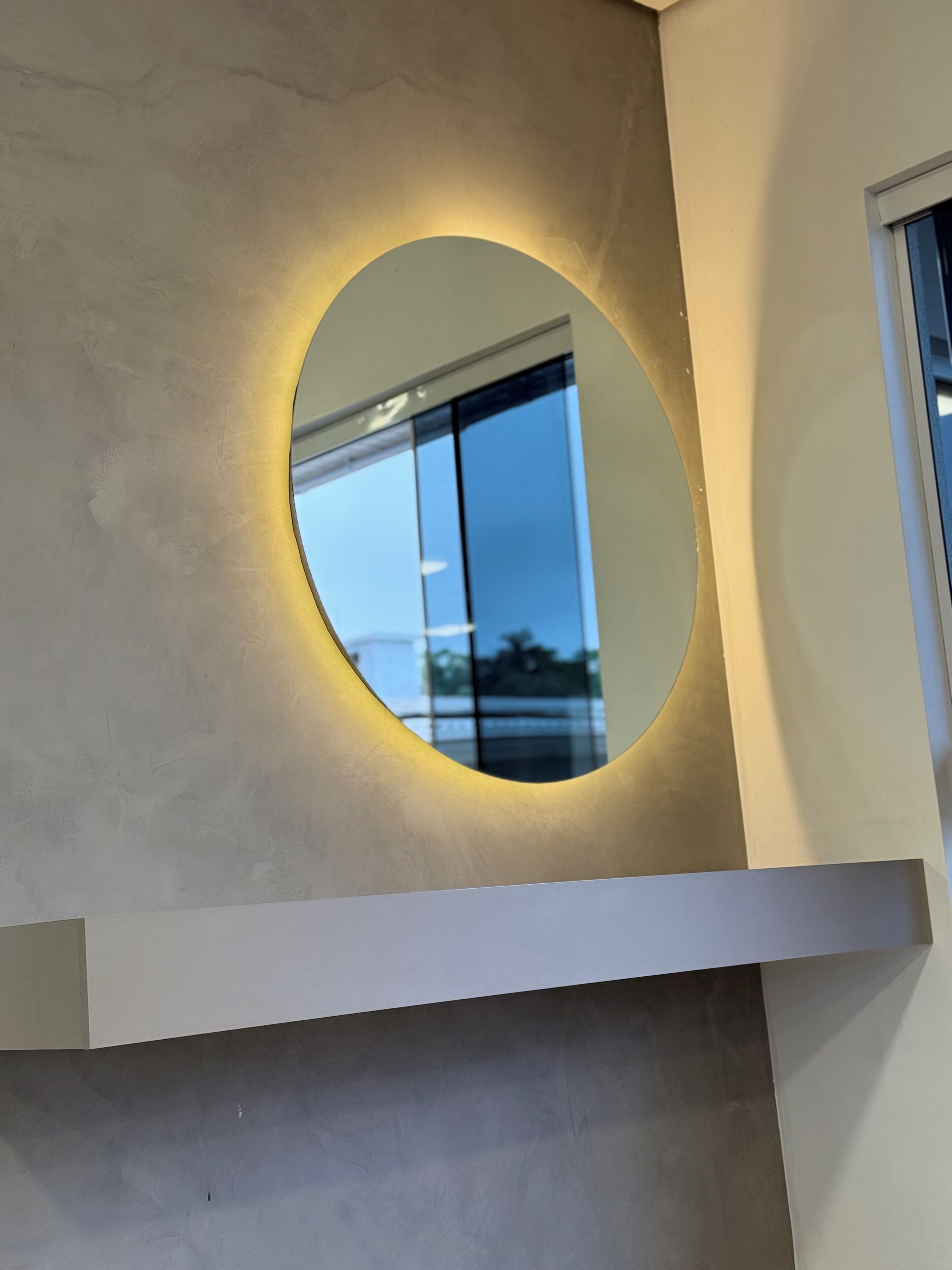 Un espejo circular con un halo de luz en la pared.