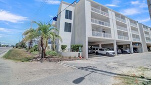 A multi-story parking garage attached to a white building with balconies. - Sugar Beach 354 (Orange Beach)