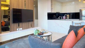 A modern living room with a flat-screen TV, a sofa, a coffee table, and a chandelier. - TIL Vinhomes D'capitale Elegance Suites (Hanoi)
