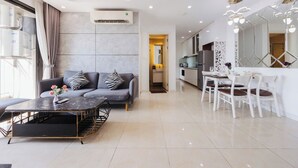 A modern living room with a sofa, coffee table, and dining area with chairs. - TIL Vinhomes D'capitale Elegance Suites (Hanoi)