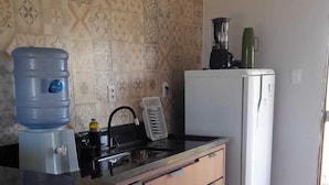 A kitchen with a water dispenser, a blender, a refrigerator, and patterned wallpaper. - FLAT SHELDOM (Maraú)