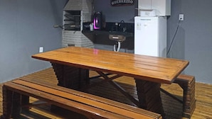 A kitchen with a wooden table, a stone wall, and a sign reading "Cantinho do Guerreiro". - FLAT SHELDOM (Maraú)