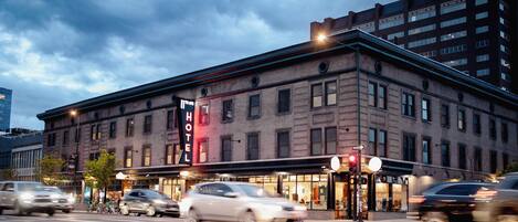 A hotel with a prominent 'HOTEL' sign, a brick facade, and a corner location with a street view.