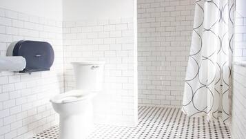 Et badeværelse med hvide flisevægge, et toilet og et gulv med et mønster.