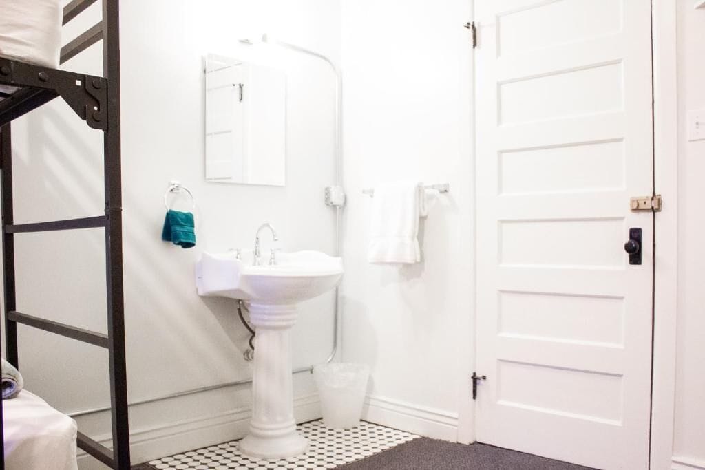 A bathroom with a white sink, a mirror, a towel rack, and a door.