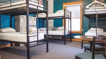 A dormitory room with bunk beds, a table, chairs, and lockers.