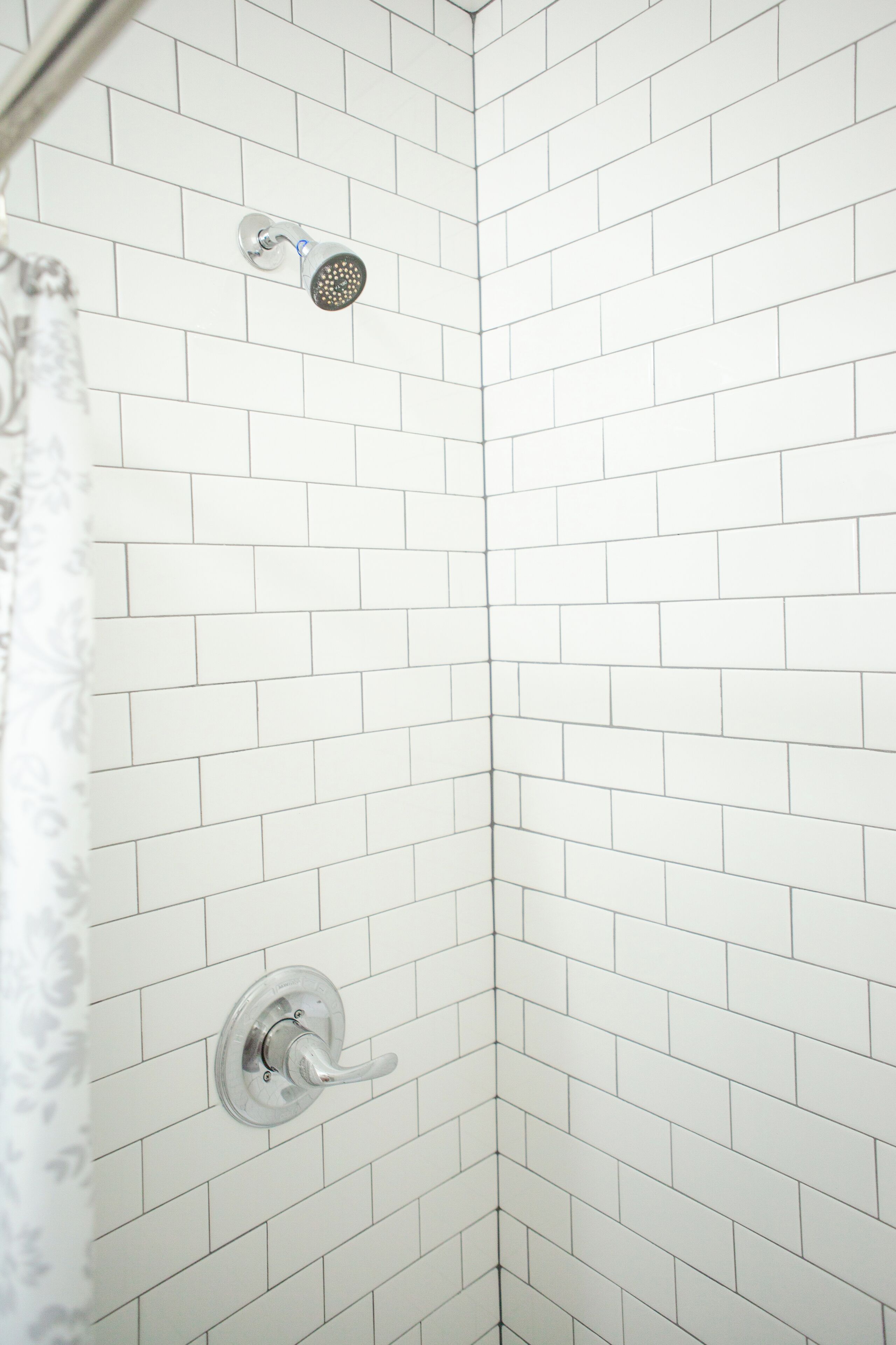 A corner shower with white subway tiles and a chrome showerhead.