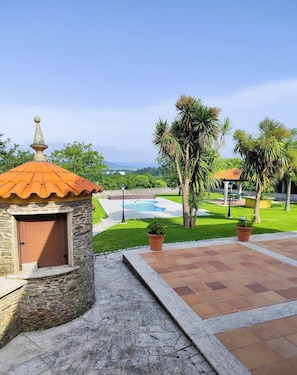 A stone building with a tiled roof, a swimming pool, and palm trees. - Donato House (Narón)