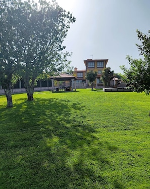 A large, multi-story building with a yellow facade, a covered patio area, and a well-maintained lawn. - Donato House (Narón)