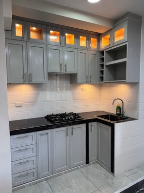 Een koelkast, een oven, kookgerei, borden en bestek