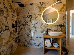 A modern bathroom with a marble wall, a round mirror, a sink, and a shower area. - Radiant and Secluded Villa With Pool (Rovinj)