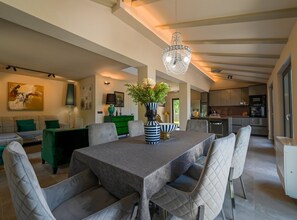 A modern dining area with a large table, cushioned chairs, a chandelier, and a green cabinet. - Radiant and Secluded Villa With Pool (Rovinj)