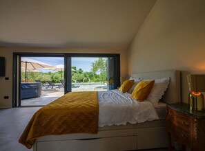 A bedroom with a large bed, a nightstand, and a view of an outdoor patio area. - Radiant and Secluded Villa With Pool (Rovinj)
