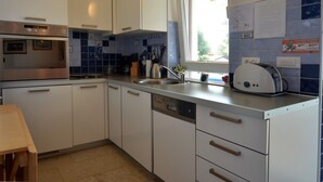 A compact kitchen with white cabinets, a built-in oven, a Bosch dishwasher, and a window with a view of the outdoors. - Comfortable and Sunny Rovinj Apartment (Rovinj)
