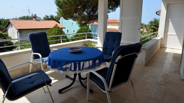A covered outdoor seating area with a round table and four chairs, overlooking a residential neighborhood. - Comfortable and Sunny Rovinj Apartment (Rovinj)