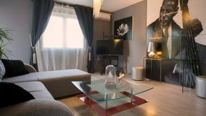 A modern living room with a glass coffee table, a sofa, a TV, and a large abstract painting. - Scenic Rovinj Apartment With Balcony (Rovinj)