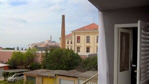 A balcony with a view of a historic town, including a tall chimney and a church spire. - Scenic Rovinj Apartment With Balcony (Rovinj)