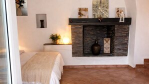 Een slaapkamer met een open haard, een bed en uitzicht.