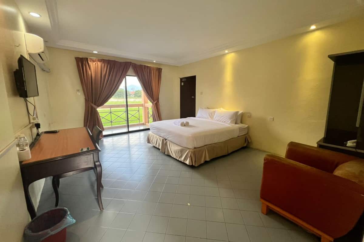 A hotel room with a bed, a desk, a chair, a TV, and a balcony with curtains.