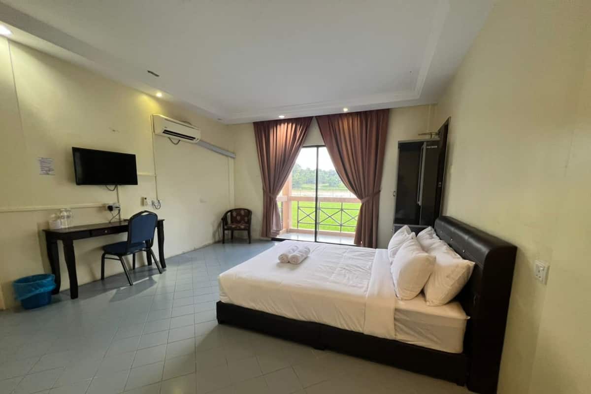 A hotel room with a bed, a desk, a chair, a TV, and a window with curtains.